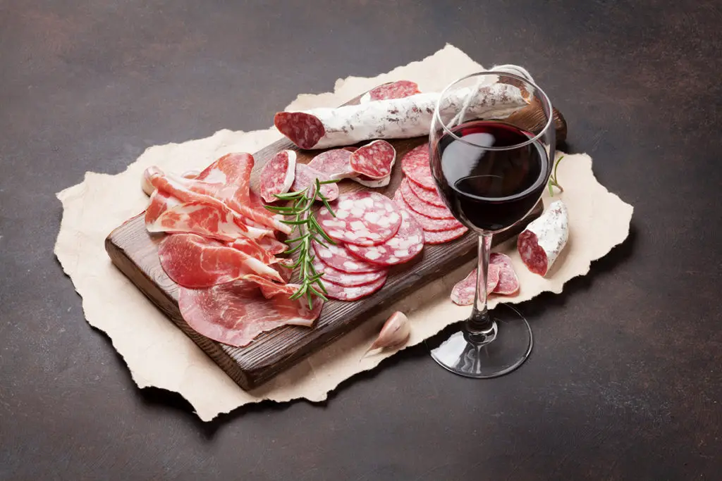 Slices of ham paired with a red wine.